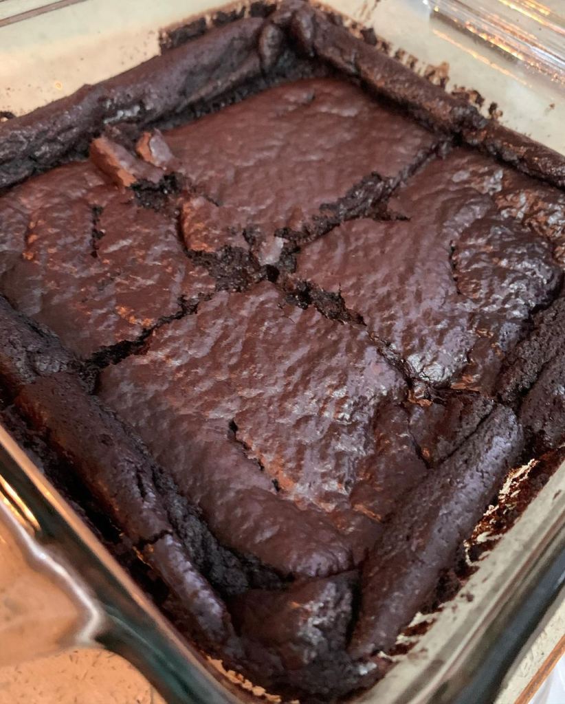 Low calorie brownies with a shiny, crinkled top created using erythritol as a sweetener in place of sugar, baked in a glass dish pan.